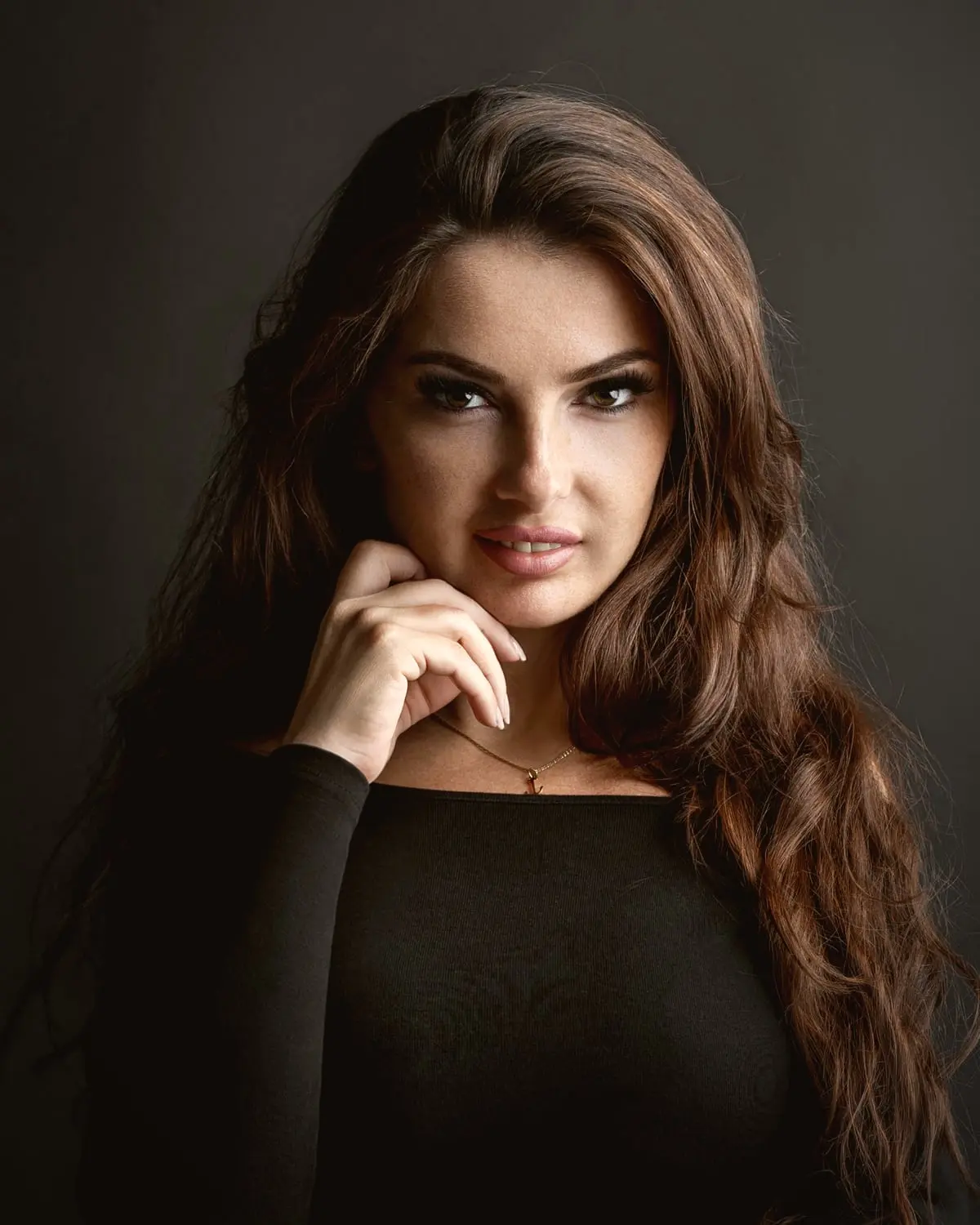 Ankica Moradi im schwarzen Oberteil vor dunklem Hintergrund, die Hand am Kinn